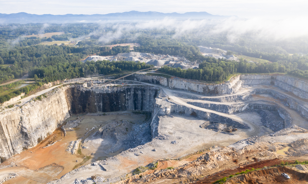 Aerial View of a Quarry & Mining Site With Trees and Mountains In the Distance