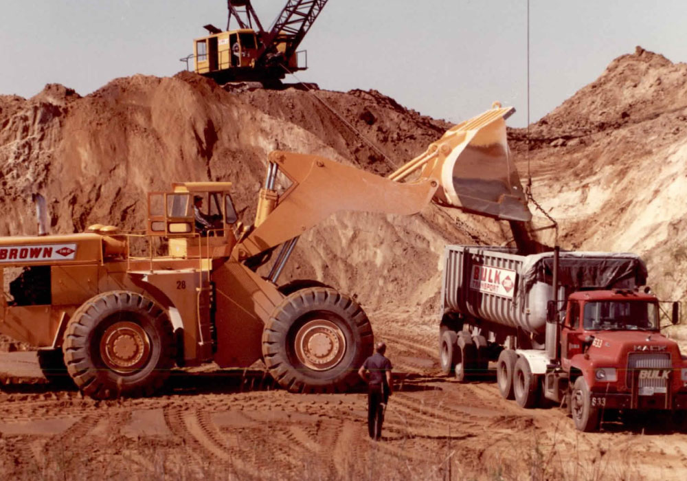 Brown's Bulldozer And Crane Loading Dirt Onto Bulk Transport Dump Truck