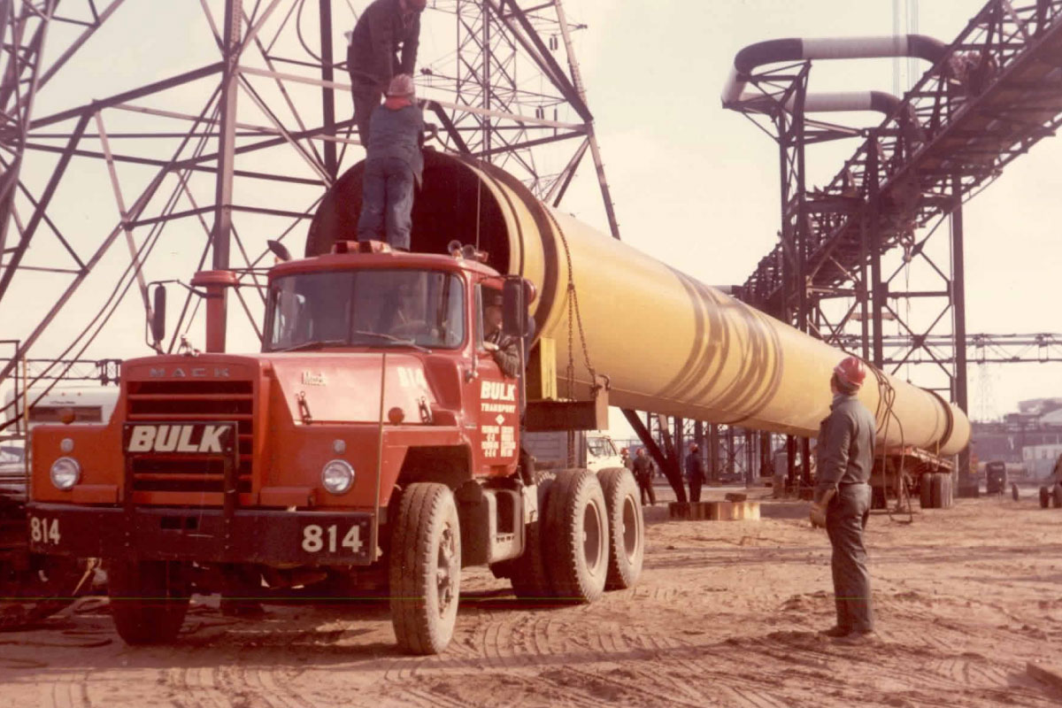 Bulk Transport Crew Loading Large Pipe Onto Truck Back In The Day