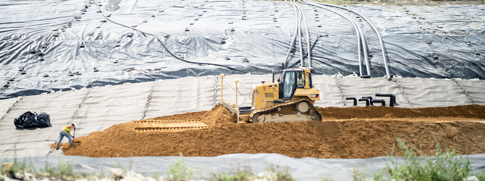 Cat® Bulldozer & Bulk Employee Moving Dirt To Cover Solid Waste At A Landfill Site